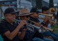 Musicians playing trumpets and trombones together at an outdoor live event