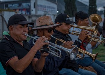 Musicians playing trumpets and trombones together at an outdoor live event