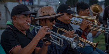 Musicians playing trumpets and trombones together at an outdoor live event