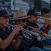 Musicians playing trumpets and trombones together at an outdoor live event